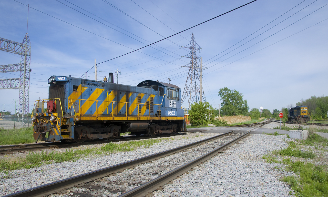 The only two games in the town of Beauharnois are visible as the ex-Port of Montreal SW1001 temporarily takes a break from its switching duties at the Axiall plant while a crewmember gets ready to throw a switch. At right CSXT 6247 is getting ready to head towards the Diageo distillery to pick up some cars.