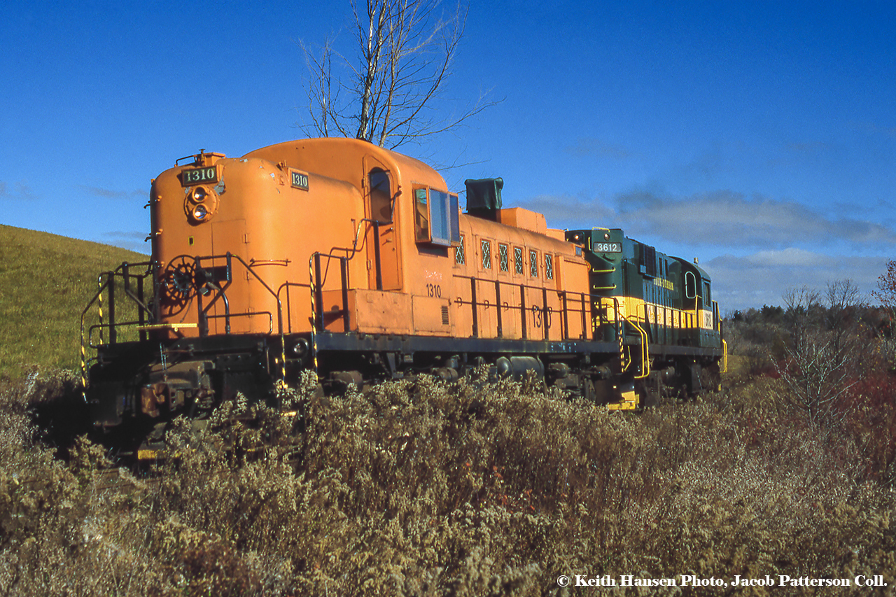 A pair of York Durham Heritage Railway ALCO/MLW products is seen having just crossed Concession Road 2 approaching the town of Goodwood. RS11 3612 is hauling newly arrived RS3 1310 along the Uxbridge Sub from Stouffville. While myself and people involved at the YDHR were unable to track down a date for this image, 1310 arrived on the property in the fall of 1996 wearing this orange scheme from it's time working for Abitibi-Price at their Iroquois Falls location beginning in 1985. Originally the unit was built in 1951 as ONR 1310, and can still be seen today, though out of service per my last visit in 2019.Keith Hansen Photo, Jacob Patterson Collection Slide.