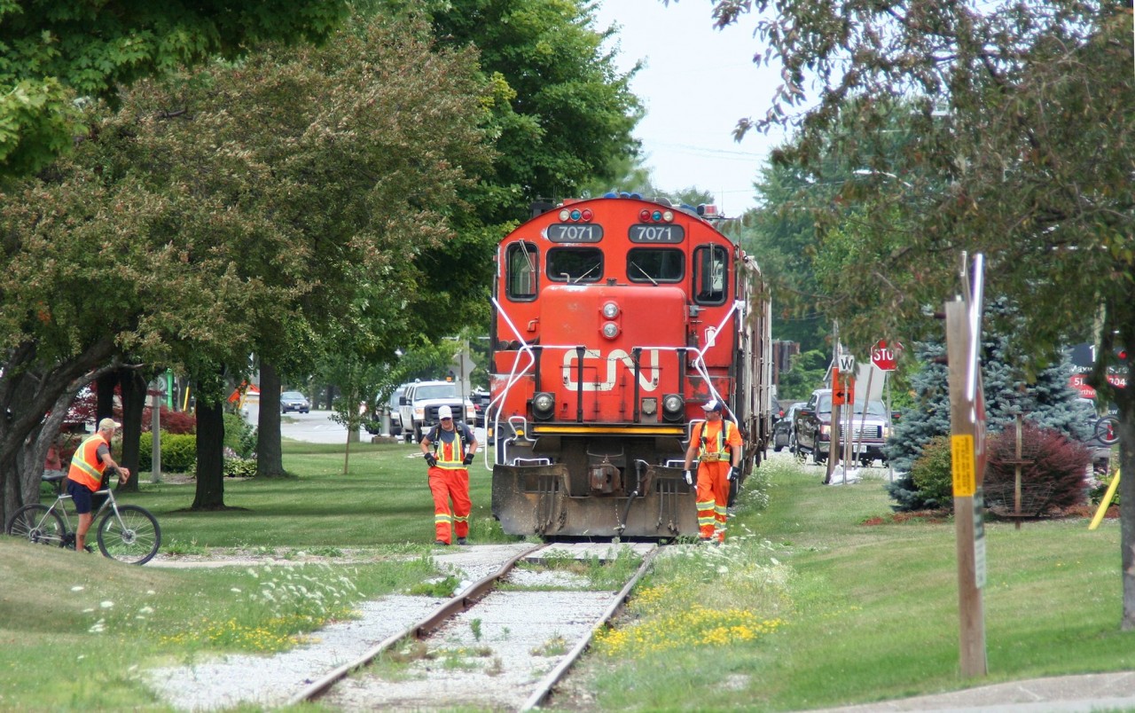 Having lifted a trio of empty hoppers at the Cargill Grain Terminal at Sarnia's harbour, the crew of the CN local job walks their train over one of many crossings as they work their way through Sarnia's downtown waterfront Centennial Park.
