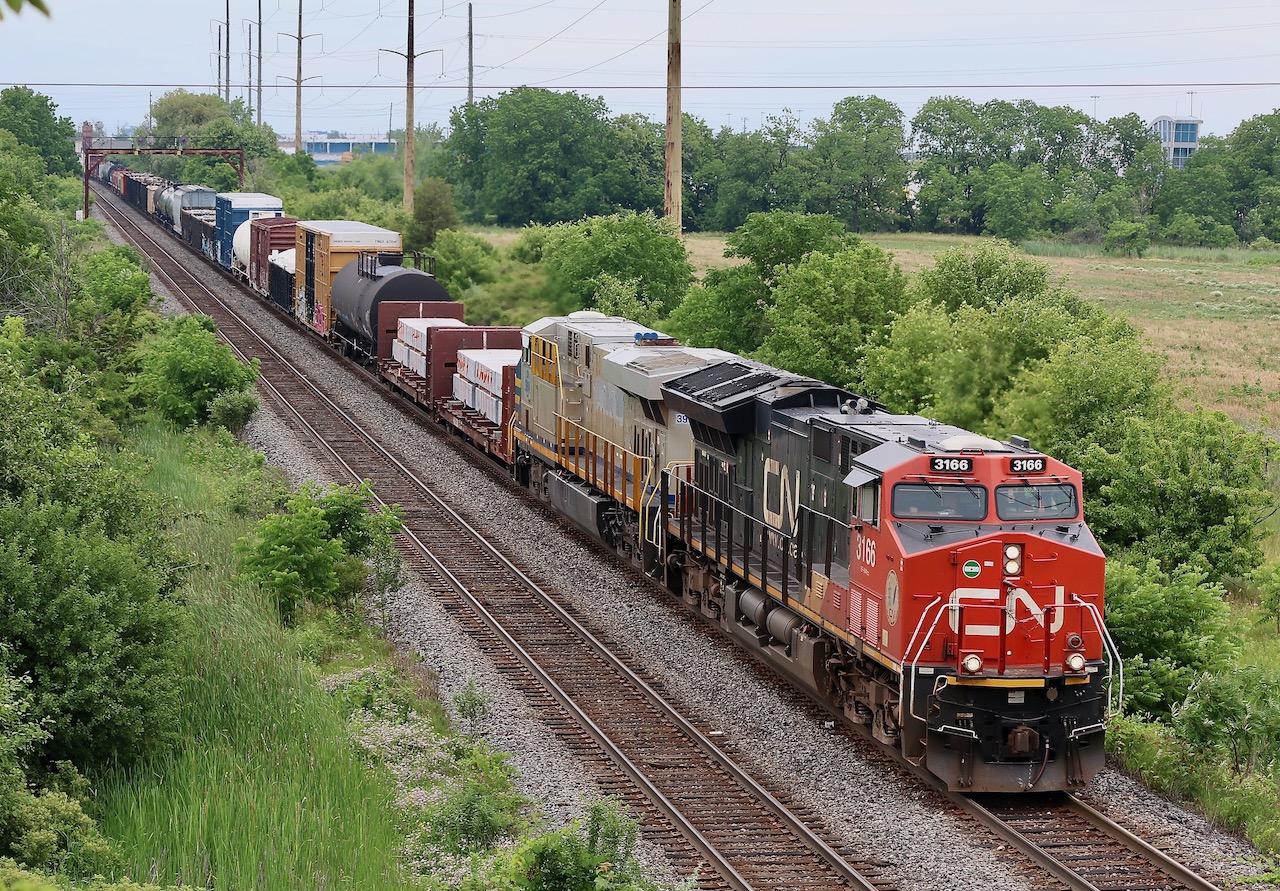 One of CN's new arrivals in the form of a former CREX/Citi Rail ES44AC, now CN 3914, trails CN 3166 as the pair along with another Gevo deep in DPU mode haul a long train 385 under Guelph Line in Burlington on a very humid June day.