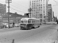 TTC PCC 4211 (an A3-class car built in 1942) heads westbound on Albert Street past Bay, operating on the Dundas route bound for <a href=http://www.railpictures.ca/?attachment_id=36016><b>Runnymede Loop</b></a> near the CPR's West Toronto Yard. It will soon swing up Elizabeth and curve back onto Dundas for the usual westbound trip. A PCC car on the Dupont route heads south on Bay in the background, passing the sprawling factories, offices and retail space belonging to the Timothy Eaton Company Limited (Eaton's). Canadian retail giant Eaton's had amassed a large cluster of buildings over time in the Queen-Bay-Dundas-Yonge area, and starting in the early 1970's many were demolished to make way for the new Eaton Centre mall and surrounding developments. <br><br> Albert Street here used to be a through street and extend west of Bay Street, running through "The Ward" (or St. John's Ward), historically a run-down neighbourhood that had been home to new immigrants and the poor/impoverished for many decades previous. At one point, the living conditions were so bad it became a health concern to the city. Much of the area had been expropriated and redeveloped in the 1920-60's. <br><br> This section of Albert Street was soon to be eliminated and built over, due to construction beginning on a new Toronto City Hall over a large tract of land northwest of Bay and Queen starting later in 1961. Dundas cars coming off <a href=http://www.railpictures.ca/?attachment_id=30851><b>City Hall Loop</b></a> (Louisa-James-Albert) and continuing west on Albert would simply be rerouted up Bay to Dundas. Today, this streetcar would be sitting in the middle of Nathan Phillips Square, in front of the current City Hall. <br><br> <i>John F. Bromley photo, Dan Dell'Unto collection negative (large-format scanned with a DSLR, with some restoration work done).</i>