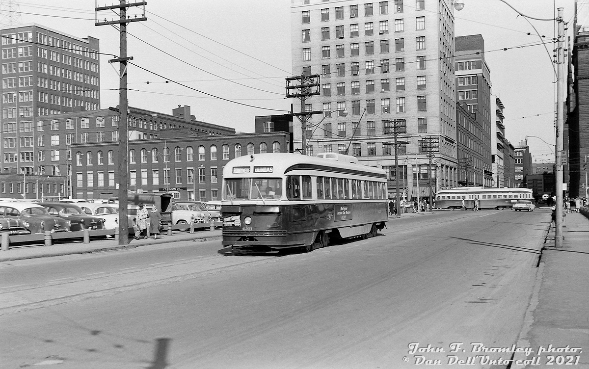 TTC PCC 4211 (an A3-class car built in 1942) heads westbound on Albert Street past Bay, operating on the Dundas route bound for Runnymede Loop near the CPR's West Toronto Yard. It will soon swing up Elizabeth and curve back onto Dundas for the usual westbound trip. A PCC car on the Dupont route heads south on Bay in the background, passing the sprawling factories, offices and retail space belonging to the Timothy Eaton Company Limited (Eaton's). Canadian retail giant Eaton's had amassed a large cluster of buildings over time in the Queen-Bay-Dundas-Yonge area, and starting in the early 1970's many were demolished to make way for the new Eaton Centre mall and surrounding developments.  Albert Street here used to be a through street and extend west of Bay Street, running through "The Ward" (or St. John's Ward), historically a run-down neighbourhood that had been home to new immigrants and the poor/impoverished for many decades previous. At one point, the living conditions were so bad it became a health concern to the city. Much of the area had been expropriated and redeveloped in the 1920-60's.  This section of Albert Street was soon to be eliminated and built over, due to construction beginning on a new Toronto City Hall over a large tract of land northwest of Bay and Queen starting later in 1961. Dundas cars coming off City Hall Loop (Louisa-James-Albert) and continuing west on Albert would simply be rerouted up Bay to Dundas. Today, this streetcar would be sitting in the middle of Nathan Phillips Square, in front of the current City Hall.  John F. Bromley photo, Dan Dell'Unto collection negative (large-format scanned with a DSLR, with some restoration work done).