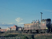 A summer evening finds a handful of green and gold GMD products in the yard at North Battleford, Saskatchewan near the CNR office.  The art deco lettering is still on the building on Railway Avenue as of 2019.  SW1200RS 1360 (GMD, 1960) would serve CN almost four decades, being retired in 1998 and sold to Canac.  Across the yard, A-1-A trucked GMD1s 1055 and 1033 can be seen.  Note the truck mounted sand boxes.  1055 (GMD, 1959) would be rebuilt to 1155 in 1991 and would be retired from CN in 1998, sold in 1999 to the <a href=https://condrenrails.com/D&R/D&R-Slides/D&R-1155-Russellville-AR-8-99-2.jpg>Dardanelle & Russellville Railroad</a> assigned to their Ouachita Railroad operation, followed by the Central Columbia & Pennsylvania, before returning to the Ouachita.  GMD1 1033 (built 1959) would be rebuilt into 1133 in 1983, and sold to the Cuban National Railway and if notes are correct, appears to have been <a href=https://www.flickr.com/photos/153712773@N08/49169895112>renumbered 51208.</a>  The rebuilding of both GMD1s into 1100 series units involved swapping the A-1-A trucks for flexicoil trucks from retired GP9s, larger fuel tanks, and other modifications.<br><br><a href=http://www.railpictures.ca/?attachment_id=40204>CN 1360 at Hamilton:</a> September 1993.<br><br><i>Original Photographer Unknown, Jacob Patterson Collection Slide.</i>