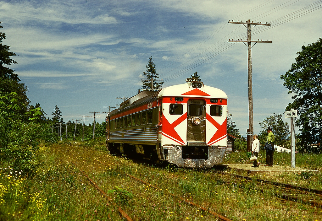 At Courtenay, the north end of CP’s Dayliner passenger service on Vancouver Island, a wye was used to turn the car to always have the baggage compartment leading, but in the Spring of 1972 that wye was removed, so changing ends became normal practice, with the result seen here on Friday 1973-06-02 as E&N southbound train No. 2 with Budd/CC&F RDC2 CP 9199 eases to a flagstop at Union Bay at mileage 130.2 of the Victoria subdivision, baggage compartment trailing but precisely on time at 1213 PDT.