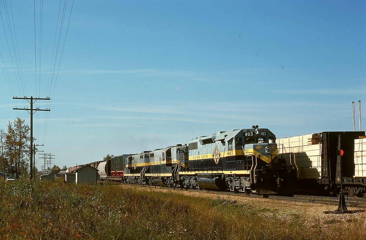 At Westlock, AB, mileage 52.2 timetable west (compass north-northwest) from Edmonton, on Saturday 1976-09-25 just before noon, train Second 40 with two GMD1s was in the clear on two tracks for a meet with No. 31 with SD38-2 403 and trailing GP9s 211 and 203 which appeared at 1225 MDT.  Of the four SD38-2s on NAR, it was normal for three to work the severe Peace River grades encountered by GSL Turns between McLennan and CN Roma Jct. while the other was cycled in rotation between McLennan and Dunvegan Yards in Edmonton for main shop maintenance.