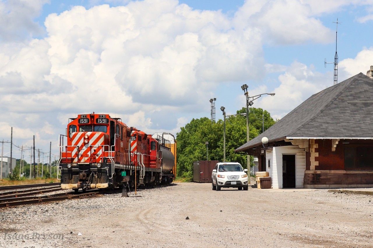 OSR 1591 and OSR 8235 (both Ex CP GP9Us) sit beside the historic Woodstock CP station as they wait for 2 cars from CP T69. At the same time, the OSR car pulls up to the station as the full crew heads into the station building. The OSR car always has a crew member and it follows the train along, dropping the crew member off in various places to throw a switch, uncouple a car, and more. This eliminates the necessary walk along the train to get back to the engines. This was the start of a chase that I partook in so hopefully more photos of this fantastic duo will appear soon!