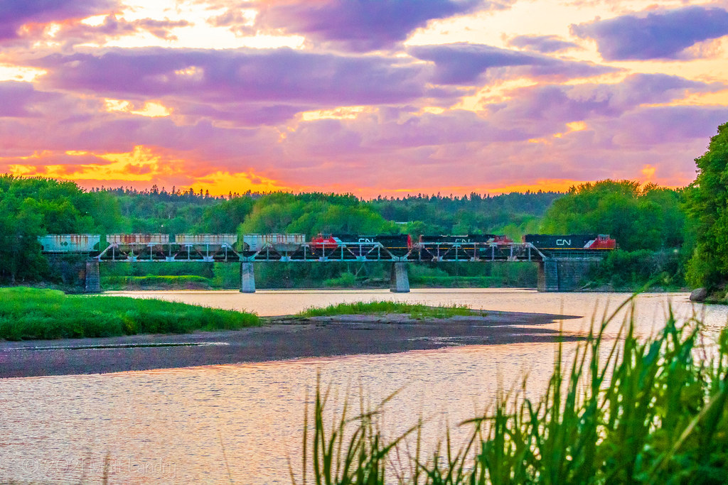 A trio of CN power haul train 406 eastbound as they haul across the trestle at Hammond River, New Brunswick with a colourful sunset filling the sky. June 12, 2021.