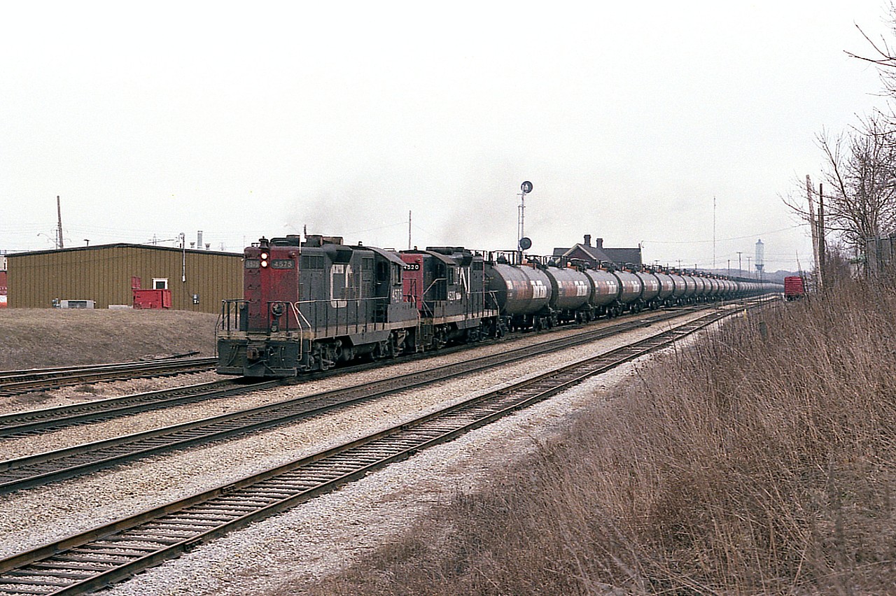 Gloomy day, but I am used to days of this kind. CN 4575 and 4520, both Geeps based out of Fort Erie, haul a unit GATX Tank Train westward past the Merritton station, destination unknown. With just two GP9s in charge, we know
the tank cars are empties.
I don't know anything about these cars, as to whether they are still used around the province or not. Just on short runs, I would assume. Do recall a cut of similar cars in an eastbound CN at Copetown a few months back. Have seen a solid train of this type only a couple of times over the years.