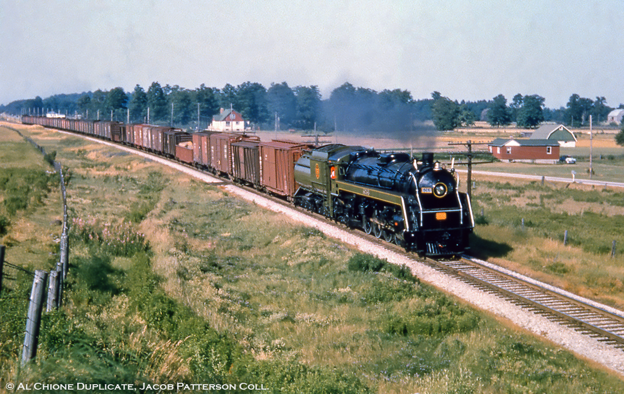 A rather sharp looking CNR U-1-f, 6069, hustles an extra freight westbound along the Brampton Sub about to duck under Jones Baseline on the approach to Guelph.  King’s Highway 7 parallels the railway at right.  Donning fresh paint, perhaps the loco has recently come out of the Stratford shop having had some work done.  Built in 1944, 6069 is now on display at Sarnia.Original Photographer Unknown, Al Chione Duplicate, Jacob Patterson Collection Slide.