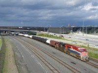 The BC Rail heritage unit leads a 132-car long CN 321 (with CN 3864 trailing) as it emerges from the Turcot interchange under dramatic skies.
