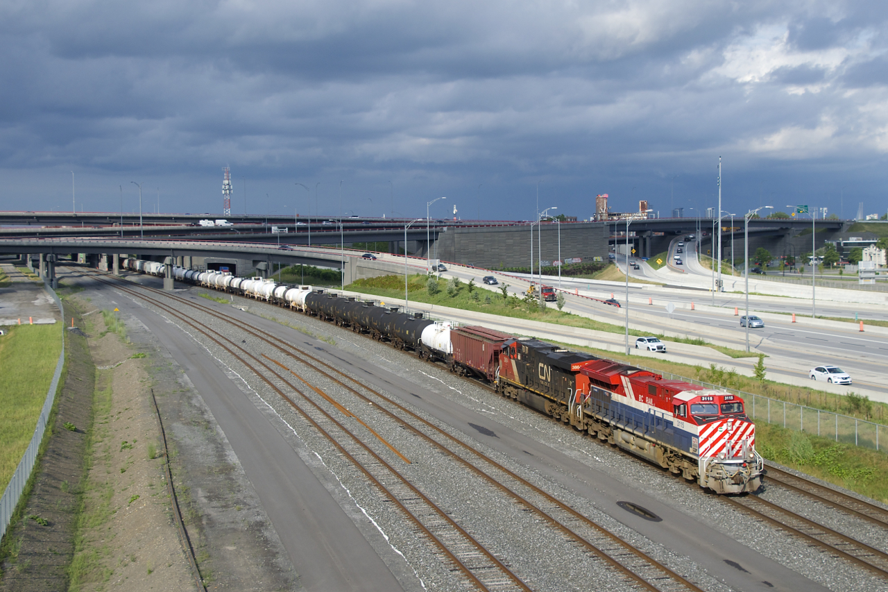 The BC Rail heritage unit leads a 132-car long CN 321 (with CN 3864 trailing) as it emerges from the Turcot interchange under dramatic skies.