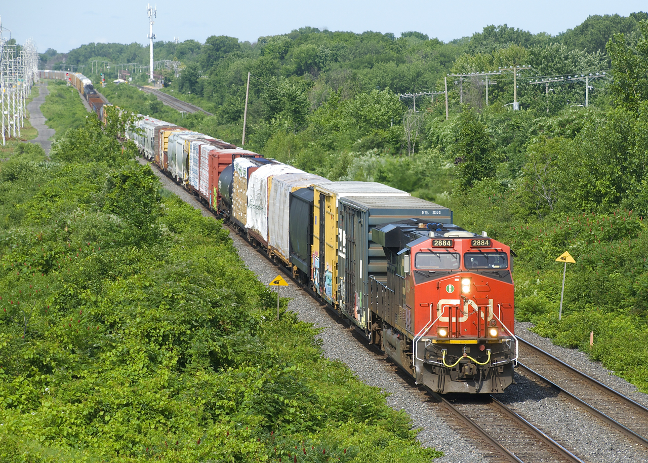 CN 2884 leads CN 322 eastwards through Beaconsfield, with CN 377 lined on the north track in the distance.