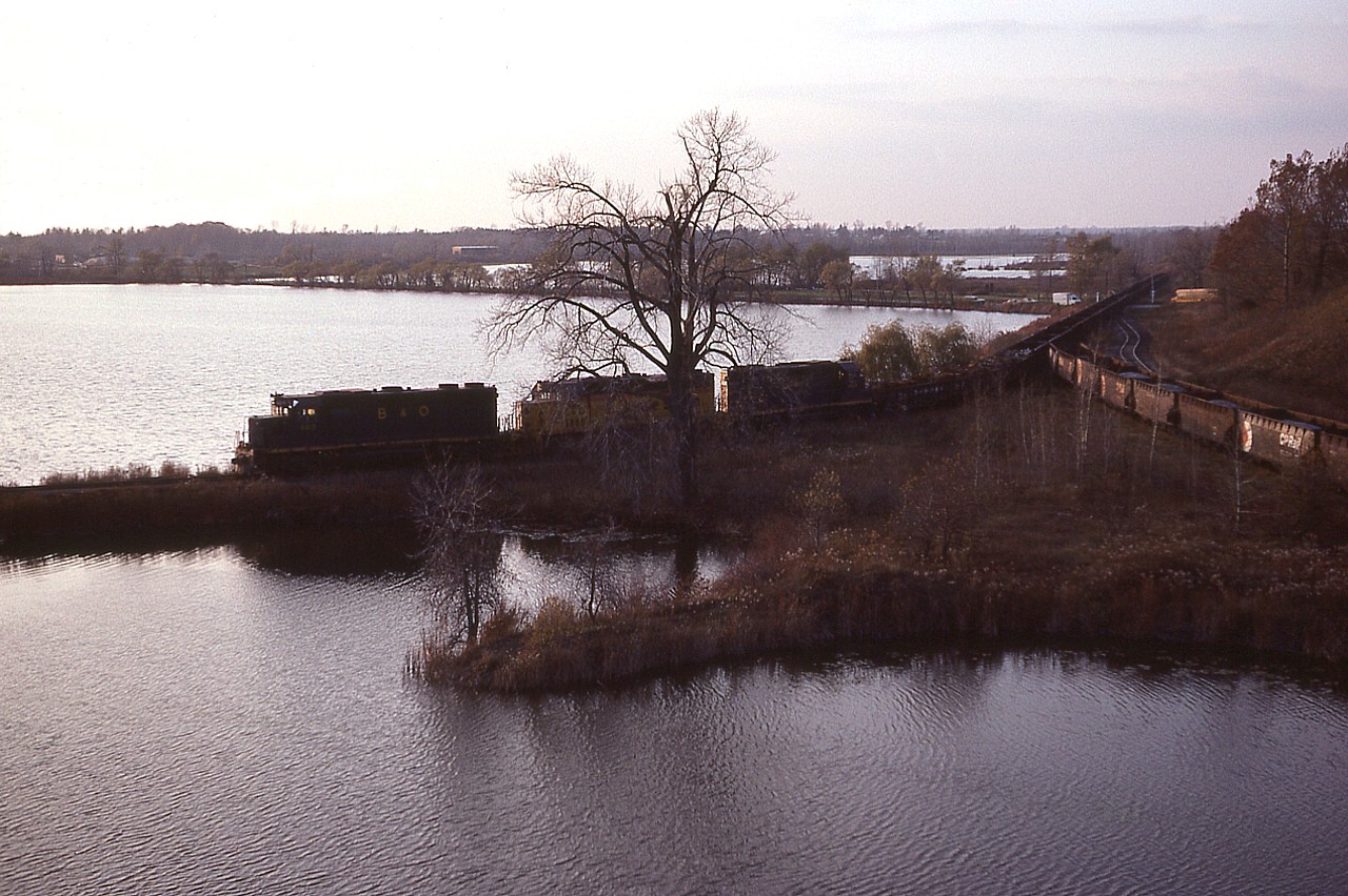 A rather interesting late day silhouette of the first TH&B routed Nanticoke steel train as it crosses Concession 8 Townsend on its way down the west leg of the wye in order to access and cross the old CASO (out of sight on the left). It was right on the verge of sundown when the train finally showed, and this vantage point off Black Bridge gave a good panoramic of just how much water makes up the 'Waterford Ponds'. B&O 3815, C&O 3885 and 4828 makes up the trains' power. These units were leased by TH&B parent CP in order to ease the demands of a very limited TH&B roster. Later, this former LE&N bridge was redecked and the out of service order lifted.