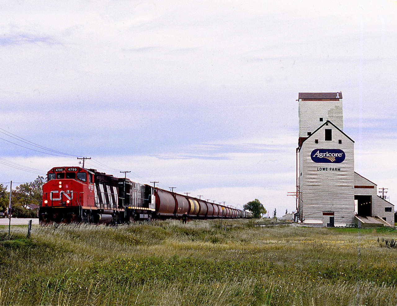 Southern Manitoba Railway Morris to Elgin grain spotter operating on former CN Miami Sub, built by Northern Pacific to reach Brandon, stops to spot elevator at Lowe Farm in the Red River Valley