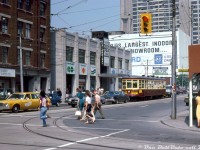 A sunny summer afternoon around 12:12pm (according to the terminal clock) finds TTC Peter Witt streetcar 2766 operating on a fantrip charter, waiting in traffic southbound on Bay Street at Dundas as pedestrians cross in the foreground (in front of a station wagon marked for "The Spectator" (Hamilton Spectator?)). The old Peter Witt is one of a handful retained, re-acquired or borrowed by the TTC for a downtown Tour Tram service that ran for a few years in the 1970's, after the last of the Witts had been retired in 1965. They were popular for transit enthusiast charters and fantrips during their reprieve, and the TTC still retains car 2766 today for rare trips out around town.
<br><br>
In the background is the the Toronto Coach Terminal, downtown Toronto's main intercity coach terminal located at the southwest corner of Bay and Edward. Operators running out of the terminal are displayed on the signage outside: GO Transit (note slightly different logo with stylish arrow), Voyageur Colonial (east coast coach operator later absorbed by Greyhound, note billboard in the background), Gray Line tours, Greyhound Canada, and Gray Coach Lines. It initially opened December 19th 1931 and served as the main Toronto hub for the TTC's interurban coach operator Gray Coach Lines (sold off to Greyhound in the 90's). As the years went by, the terminal proved to be a poor location due to its distance from major highways (QEW/Gardiner/Hwy 427/Hwy 401) and the need for buses to navigate busy downtown traffic.
<br><br>
GO Transit began its own bus operations here in 1970, but in the 90's moved to loading right outside of Union Station on Front Street, until a new bus terminal opened in 2001 (the site of the old CP Express Building). GO recently moved into yet another new bus terminal south of the rail corridor in December 2021, its bus services out of Union outgrowing the previous one!
<br><br>
For the longest time, Greyhound Canada had been the main tenant of the Toronto Coach Terminal. But that all changed when they suspended all Canadian operations due to the COVID pandemic in May 2020, and announced a year later in May 2021 that they would be ceasing all of their Canadian operations permanently. Ontario Northland's bus service was the final operator to use the terminal, but it wasn't long before they moved to the new GO bus terminal downtown, and the old Toronto Coach Terminal on Bay would close on July 4rd 2021. The main building and lobby area (that had underwent restoration) is on the city's heritage register, so it is expected it would be retained and incorporated in whatever redevelopment plans will follow.
<br><br>
<i>Photographer unknown, Dan Dell'Unto collection slide.</i>