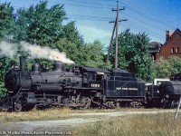 A vintage, home built New York Central F-82 ten-wheeler is seen working the yard in Petrolia.  The 4-6-0, built by the Michigan Central Railroad at the St. Thomas Shops in July 1900 as MCR 449, later MCRR 8152 (1905), NYC 880 (1936) and finally NYC 1290 (1947) had served as a passenger engine for many years until being bumped to way freight service on the St. Clair Branch.  1290 would make its last run on April 27, 1957. <br><br>The 66.38 mile <a href=http://www.canadasouthern.com/caso/ett/images/tt-0459.pdf#search=%22St%20Clair%22>St. Clair Subdivision</a> was built from Courtright (mile 66.8) on the shore of the St. Clair River to St. Clair Junction (mile 4.23), the connection with the main CASO Division.  Miles measured from St. Thomas.  Originally laid down in 1873 by the Canada Southern Railway and opening in 1874 as a way for the CASO to access the oil deposits of Lambton County, the line connected communities including Alvinston, Oil City, Brigden, and Courtright, plus Petrolia via the Petrolia Spur.  The 12.04 mile Petrolia spur branched north off the St. Clair Sub a couple miles west of Oil City, terminating in Petrolia eventually having a connection to the CNR, whose station (GWR) sits <a href=http://www.railpictures.ca/?attachment_id=29596>just 2 blocks to the east</a> of this NYC shot.  The 1290 is seen beside St. Paul's United Church (built 1899) at the corner of Petrolia Line and Albany Street.  Albany Street would be built over the NYC right of way after its removal in the early '60s.  After retirement of the ten wheelers in 1956 and 1957, service on the St. Clair Sub was carried out by a number of GP7s <a href=http://www.canadasouthern.com/caso/images/abandonment-notice.jpg>unttil abandonment</a> on May 1, 1960.<br><br>More shots of 1290 courtesy of <a href=http://www.canadasouthern.com/caso/home.htm>Canada Southern website</a> which show the auxiliary tender better.<br><a href=http://www.canadasouthern.com/caso/images/nyc-1290-23.jpg>1290 on a passenger run.</a><br><a href=http://www.canadasouthern.com/caso/images/nyc-1290-39.jpg>1290 hauling freight.</a><br><br>Information per <a href=http://casostation.ca/locomotives-1290-1291/>North American Railway Hall of Fame</a> and <a href=http://www.canadasouthern.com/caso/home.htm> the Canada Southern Railway website.</a><br><br><i>Richard R. Wallin Photo, Jacob Patterson Collection Slide.</i>

