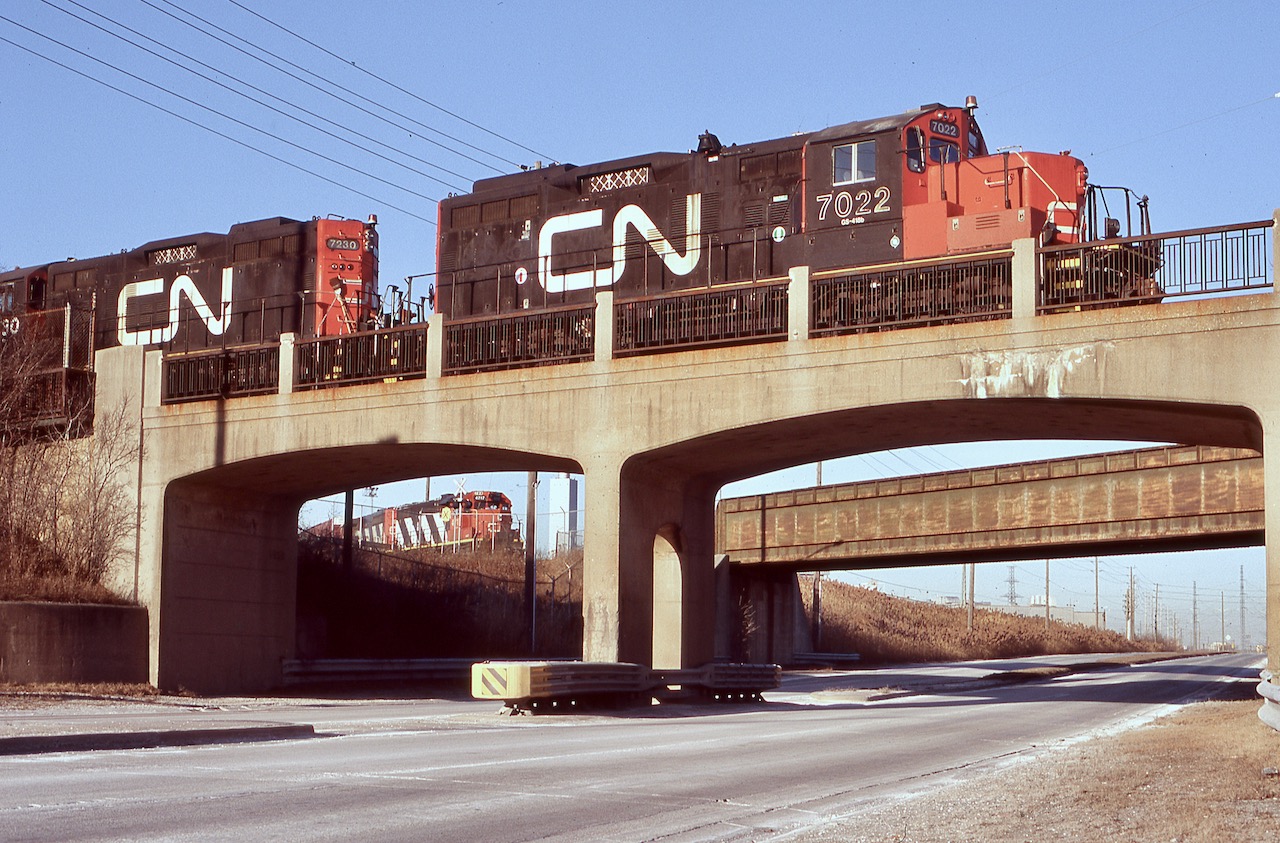 The only time I have been able to catch two CN jobs working the Ford assembly plant in Oakville. This day the job in the foreground was shuffling auto racks , while in the background another job was bringing a cut of hi-cube parts boxes back to the yard. The old bridges here cross Royal Windsor Drive and are original from when the assembly plant was built.