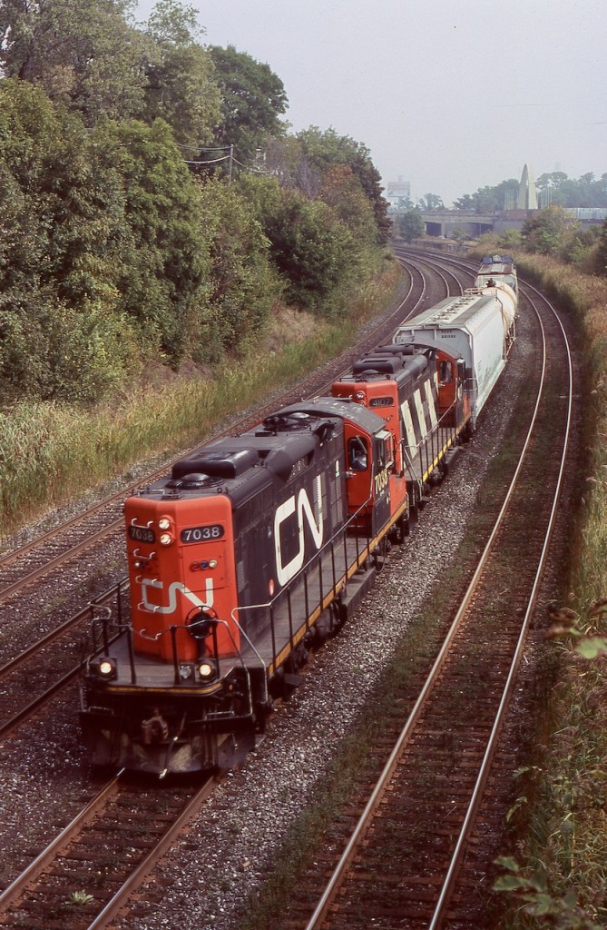 This was one of those rare lucky trips back from Toronto that actually graced me with a freight train. By this date freight activity through downtown Toronto was rare to come by, although much worse these days. Sadly almost all rail served industries near Toronto's downtown core have vanished in recent decades, with most factories either demolished or repurposed. This also led to the demise of CN Don yard on the Eastside of downtown, today it is a GO/Metrolinx storage yard, and it appears that the Portlands no longer has rail service either. Back in 2007 CN still ran at least one local between Mimico and Don yard along with through trains 434/435. This day long hood forward GP9RM 7038, and 4107 (with spark arrestors still intact) have a very short train in tow as they roll along the Gardiner Expressway and past the Exhibition's Dufferin Street gate with its arch in the distance. The train will soon arrive back at Mimico yard. Today with the Oakville subdivision east of Burlington West under Metrolinx ownership, freight traffic during the day is scarce. There is only one local job currently that works east of Clarkson, and sadly this only happens under the cover of darkness, and typically only travels as far east as Mimico.