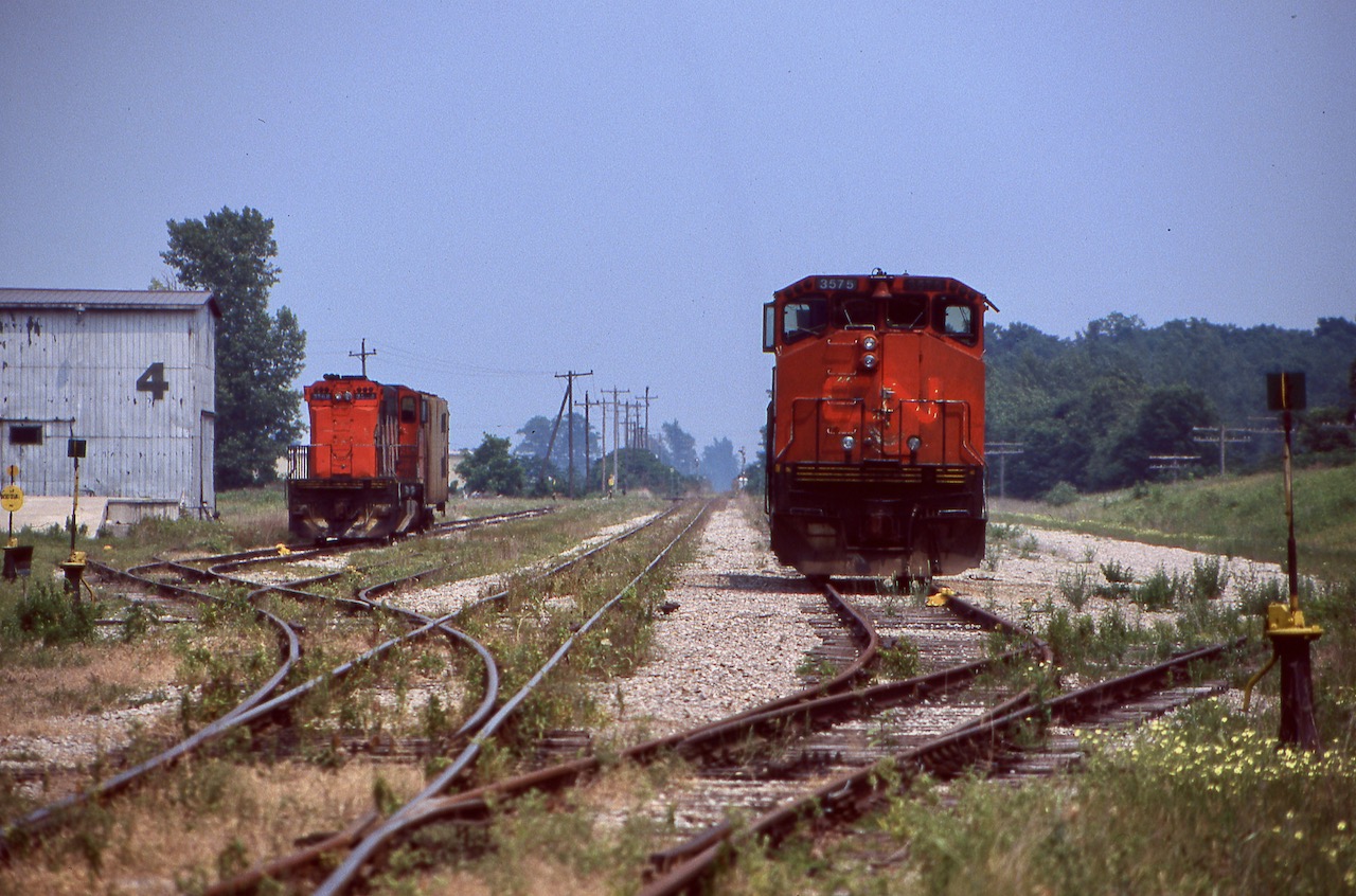By mid 1999 the Cayuga subdivision had already seen a few years pass since any trough traffic traveled across the line. Trillium operations here were just over a year old and the tracks were gone east of Delhi. The yard sure looked empty this day and most of the rails on the south side were gone. The signals in the distance once protected the CP diamond removed about a decade earlier when CP's line south of here was abandoned. The tobacco shed to the left will be replaced in the not too distant future by a new translating facility. M420 3568 would spend a number of years traveling the line, but sister 3575 would find itself relocated to British Columbia to join a group of other M420's with the shared Trillium/Night Hawk controlled Kelowna Pacific RR. Trillium would eventually split up wth the KPR venture as well as end its ties with the NYLE and both M420's would end up eventually States side. Today what is left of the Cayuga subdivision sits weed choked and unused after OSR ended its operations here when it took over for Trillium in 2016, and the rails may never see the passage of a train again.