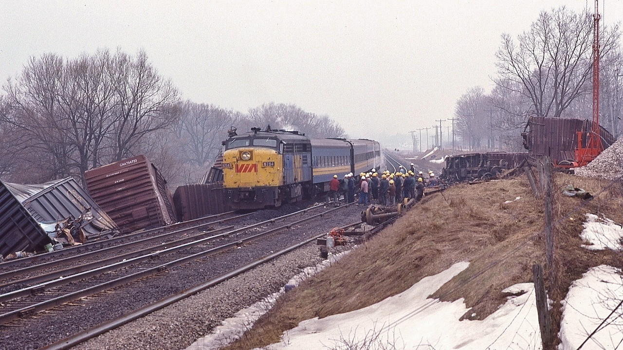 ….after moving the damaged box car off the right of way, the CN track crew of 33 takes a breather to watch an east bound VIA ... 6764 ….


   ... so it appears....


   At CN Beachville, February 18, 1984 Kodachrome by S.Danko


   Noteworthy: 


February 14, 1984: A 25 car CN train derailed four miles west of Woodstock ( Beachville) causing $1 million damage. Half mile track torn up, propane tankers included in consist. Heavy rains blamed for weakening the track bed. Reportedly every spring new remnants of the derailment can be seen along the Beachville Thames River Trail – pushed up by the winter frost.
