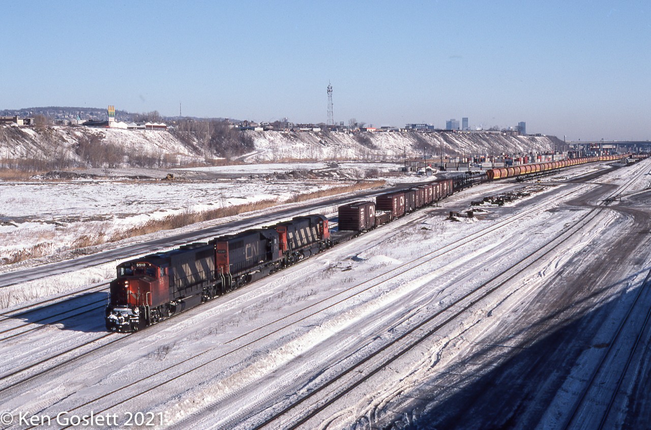 A westbound freight from the Maritimes pulls through Turcot yard in Montreal behind a GP40-2L, SD40, C-630M power set.  Included in the train is a string of government grain cars.
