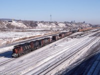 A westbound freight from the Maritimes pulls through Turcot yard in Montreal behind a GP40-2L, SD40, C-630M power set.  Included in the train is a string of government grain cars.