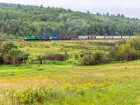 NBSR 6401 powers train 907 through the fields at Clarendon, New Brunswick. 