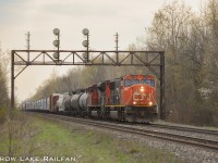 CN 5744 leads an eastbound manifest train past the searchlight signal gantry outside of Cardinal at the start of Summer.