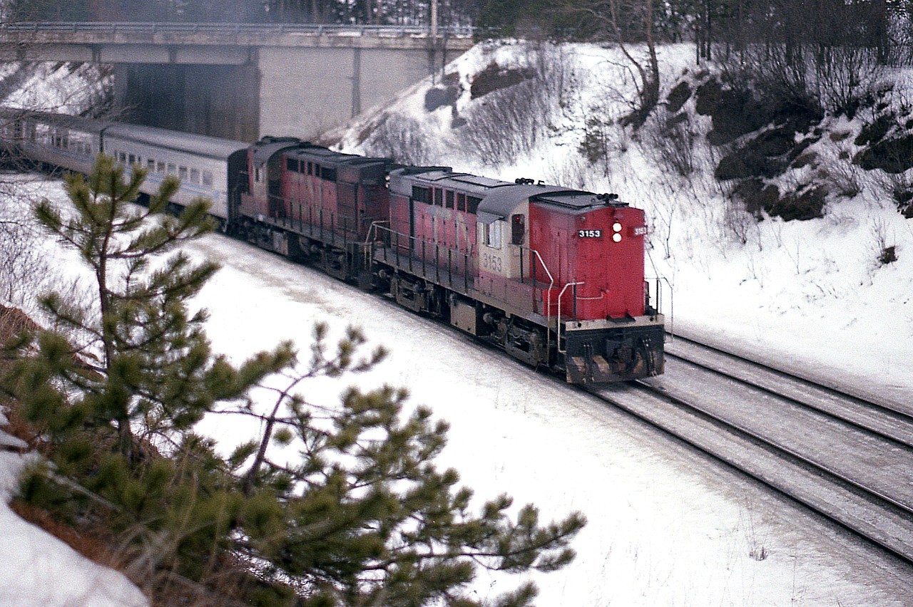 Another dreary winters' day. But then, it is the middle of a February.  "Off the hill" comes CN 'Tempo' engines 3153 and 3154, drifting toward the junction with an eastbound passenger. I trundled up into the snow covered hillside for a different angle. And got soaking wet feet. Just another day back then, and makes for pleasant  memories.