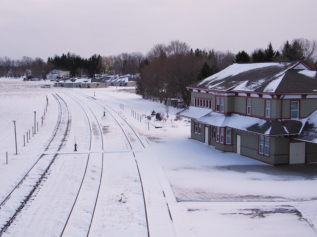 Compared to Jason Noe's photo  Palmerston was all but quiet in this cool wintry scene 9 years after CN removed the rails. The station was beautifully restored, and sits well preserved still overlooking the grounds that once housed the expansive yard, roundhouse, freight shed and numerous other railway structures that disappeared through time. Thankfully, CN left some of the tracks in place, at the front of the station for the town's annual handcar races. And, the old iron bridge was also spared. But, as peaceful as this scene is, a hint of grief remains at the memory of the trains that once rolled through Palmerston.