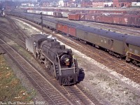 Canadian National 5299, a J7c-class Pacific (built by MLW in July 1920, scrapped March 1959) assigned to passenger service out of Spadina Roundhouse is seen reversing onto one of the yard leads near the engine servicing facilities in downtown Toronto, looking west off Spadina Avenue sometime in the mid-late 1950's. CN's Spadina Coachyard is located to left out of view, its wash racks visible in the distance.<br><br>Two tracks over on one of the main tracks leading from Union Station, a CN steam engine pulls a passenger train with the usual CN-painted equipment, plus some NYC-painted Pullman sleepers, a Lehigh Valley RPO, and a CN RPO (lettered "Mail & Express").<br><br>Further back is CN's Bathurst St. Yard full of freight cars, predominantly a mix of 40' steel and wood boxcars: CN wafer logo cars, CPR stepped lettering cars (being interchanged with CN), a Northern Pacific outside-braced wooden boxcar, and a D&LW "Route of the Phoebe Snow" boxcar. A bunch of silver-grey CN 40' ice reefers are also present. One can just pick out the red farm equipment on flatcars coming from Massey Ferguson in Parkdale sitting near the west end. And in the upper right, a glimpse of the top of a CN diesel switcher hiding in the yard.<br><br>Buildings and houses along the elevated Front Street run along the background, meeting up with Bathurst St. and its bridge over the rail corridor on the upper left.<br><br><i>Original photographer unknown, Dan Dell'Unto collection slide (an unlabeled, undated and slightly faded Anscochrome that needed some TLC).</i>