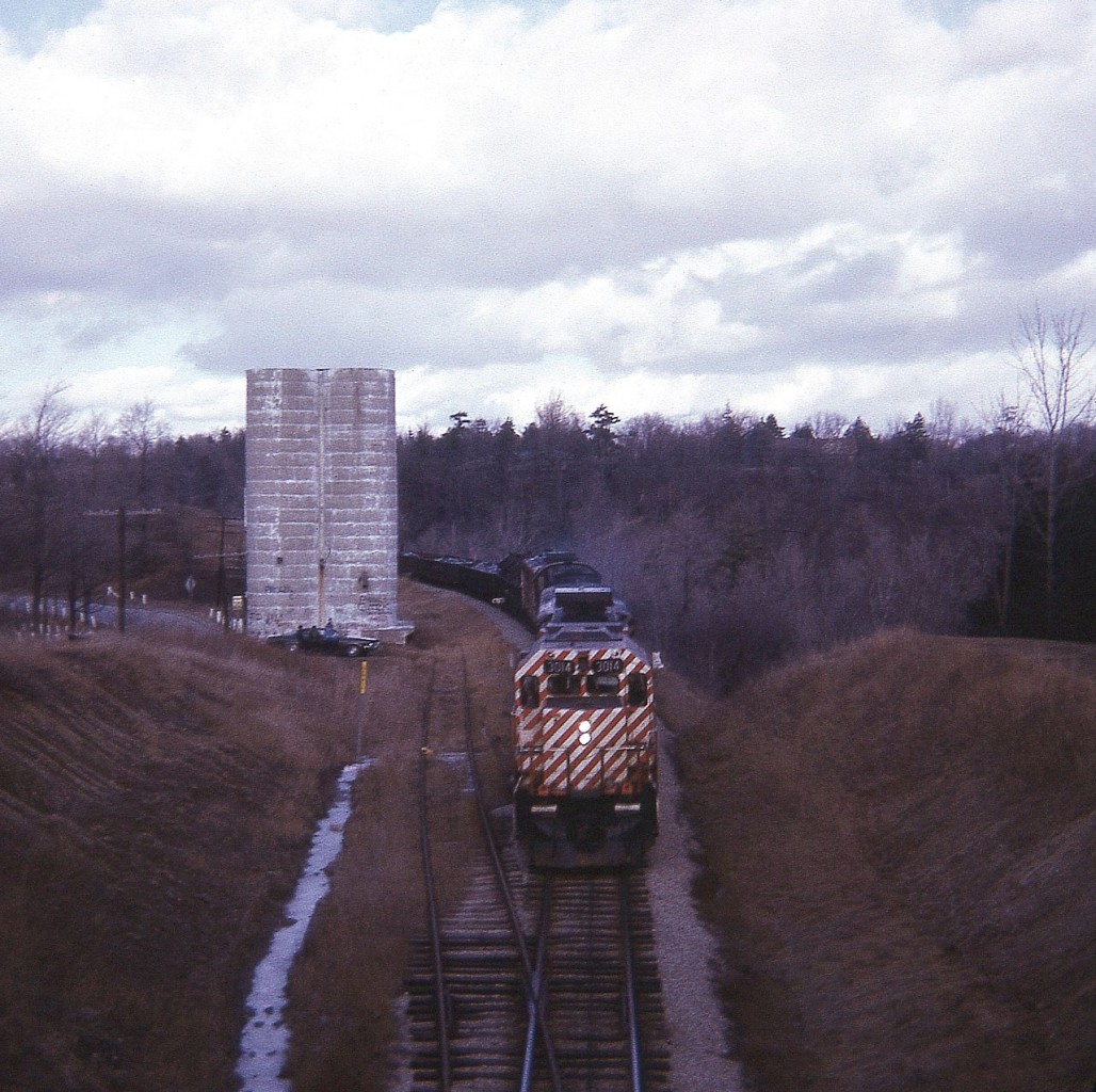 As I put this shot to RP I get to wondering how many train buffs recall an old grain silo and corresponding siding in view looking north off that old wooden bridge that spans the CP in Waterdown. The location is where Snake Rd meets Main St., which is just off to the left in this image. We're going back 47 years, and its days were already up, by the look of it. Unfortunately this image is from before I carried a notebook, and only from a blurred previous image was I able to discern the units behind the GP38 leader #3014 are two F units sandwiching an old RS-3. Incredible, really, that 3014 is still on the roster; having flirted with retirement back in 2013-2015, but ventured back on the road again.