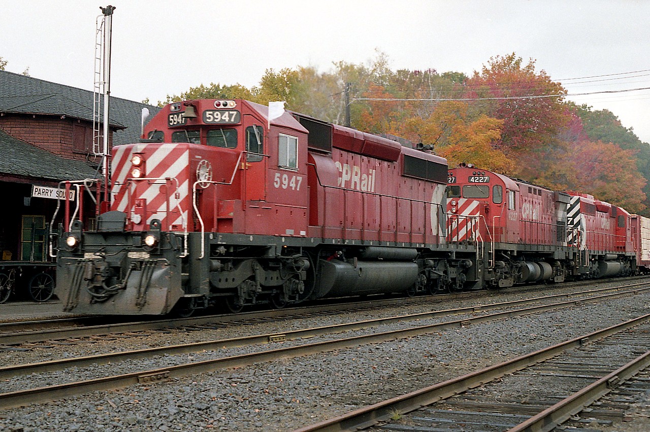 I don't remember why I was so late grabbing this shot; but the southbound, err..make that EASTbound trains drift down around a curve just before the station. I might have been snoozing on the rocks opposite the station and not heard it until the last minute.  Best excuse I can think of. The rocks were a nice comfortable place to lie back and listen to the scanner when I felt I should not be wandering in and out of the station.
Anyway, just in the nick of time, before the train blocked out the "Parry Sound" sign; CP 5947, 4227 and 5517 look good on a nice fall day.