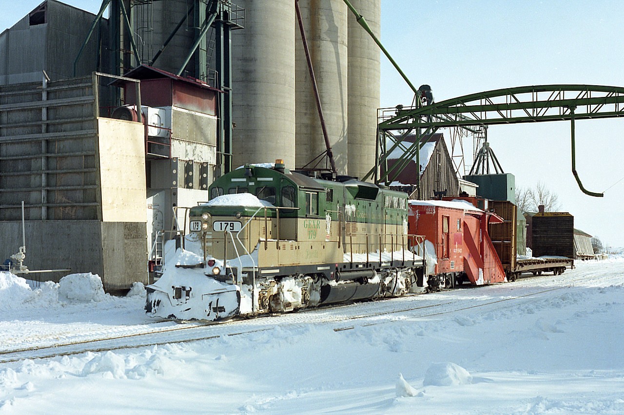 Just what we need. A winter scene to relieve the thoughts of stifling humidity these days.  This image was taken in Centralia, in the depths of winter. GEXR 179 with x-CN plough 55437 has just cleared the line to end of track, not too far south of this view. A lone car was picked up and will be dropped at Hensall.
I don't believe there is any rail activity thru this village any more. When I visited here last spring, it looked abandoned. Rust and weeds was about the size of it.
The "station" is now gone. The fact you can see it in the background, with its covered in front; is the clue to the location of this photo.  I would assume the old building was used for storage. Centralia's business days with the railway have been left behind.
