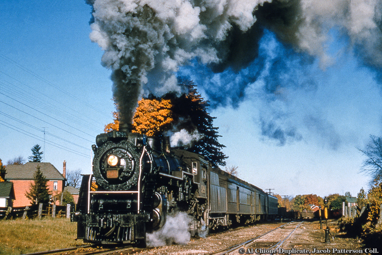 Just beginning it's run, CNR J-7-c Pacific 5299 (built by MLW in July 1920) heads up Owen Sound - Toronto train 172 departing Palmerston at 0810h.  Having departed Owens Sound that morning at 0550h and arrived Palmerston at 0800h, the train will lay over for 10 minutes to allow a change of engines up front.  Smaller Pacifics and Ten Wheelers worked the Owen Sound Sub, and these would be changed out for the larger Pacific at Palmerston.  From here, 5299 will hustle the train to Toronto, arriving at 1110h.  In barely 6 months, 5299 will be cut up for scrap in March of 1959.The switch stand nearest the photographer allowed trains to depart Palmerston yard onto the Fergus Sub mainline (where 5299 is), or while lined for the normal position (as in the photo), allows for trains working in the yard to have headroom up to King Street behind the photographer.  Immediately north of this switch, the first track off to the right leads to the coal dock and sand house, while subsequent ones lead to the roundhouse and yard tracks.5299 was a Spadina-based locomotive working passenger assignments to Hamilton and Palmerston (and likely other runs as well).  See 5299 here departing Hamilton in 1958, and approaching the Spadina overpass in Toronto here.Original Photographer Unknown, Al Chione Duplicate, Jacob Patterson Collection.