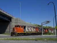 The Pointe St-Charles Switcher has a single boxcar for Kruger as it crosses Notre-Dame Street with CN 4771 & CN 4808 for power as the conductor gives a wave.