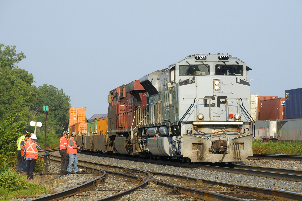 CP 143 is stopped in Dorval due to issues with the leader (Air Force unit CP 7023) as crewmembers and shop forces look on. After more delay and having to set off a car, the train would continue to Smiths Falls where further problems with CP 7023 would cause it to be moved to trail position. At right are two stopped intermodal trains on the CN Montreal Sub (CN 108 & CN 186).