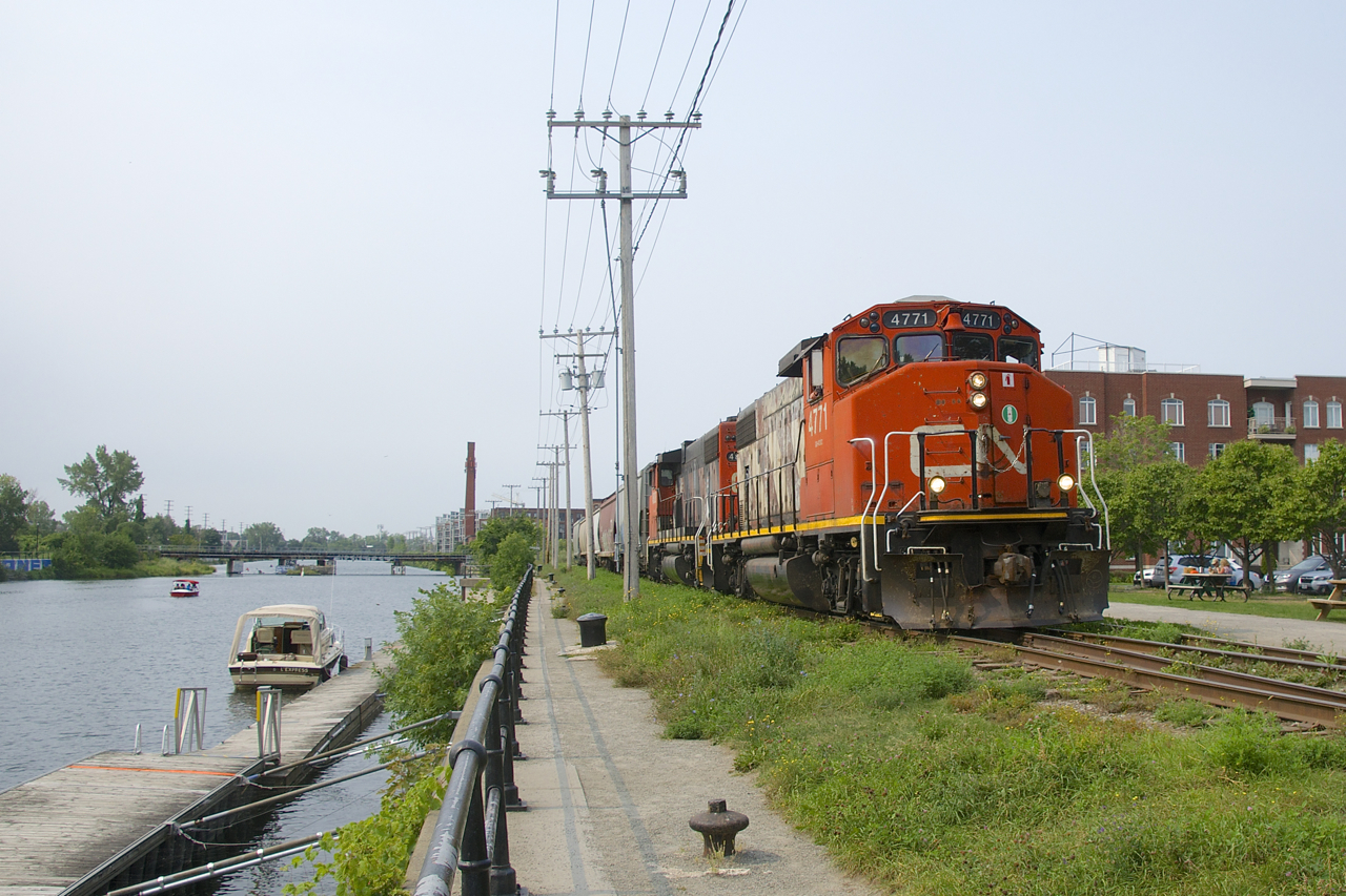 CN 4771 & CN 4808 have just arrived on the East Side Canal Bank Spur with five grain loads for Ardent Mills, at left is the Lachine Canal and in the background is CN's Montreal Sub crossing the canal. Normally this train would arrive from Pointe St-Charles Yard and shove the loads towards the client. In this instance they picked up the cars on track 29 and arrived power first; they are about to run around the cars so they can shove them to the client.