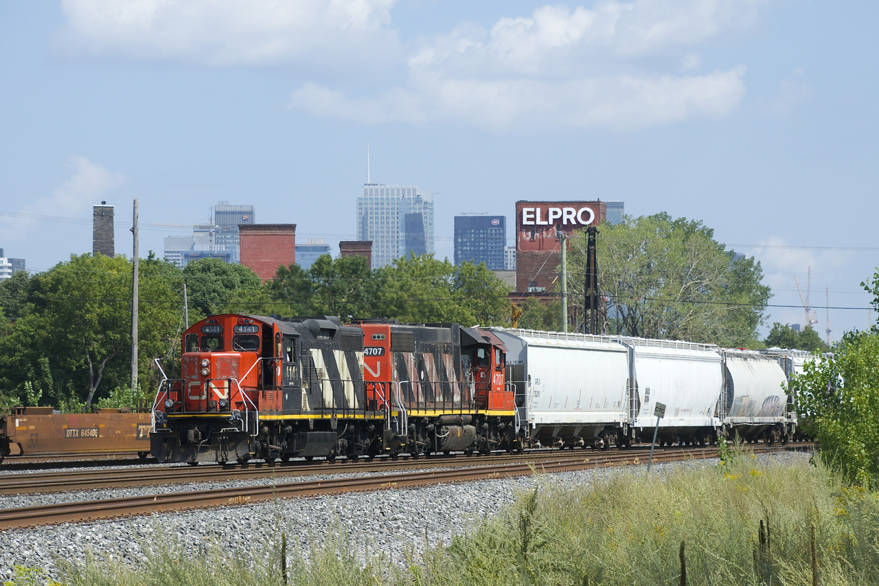 CN 4141 & CN 4707 are heading towards Taschereau Yard with 49 cars. A baretable can be seen at left, part of a CN 599 which will head to the Port of Montreal once numerous trains pass it first.