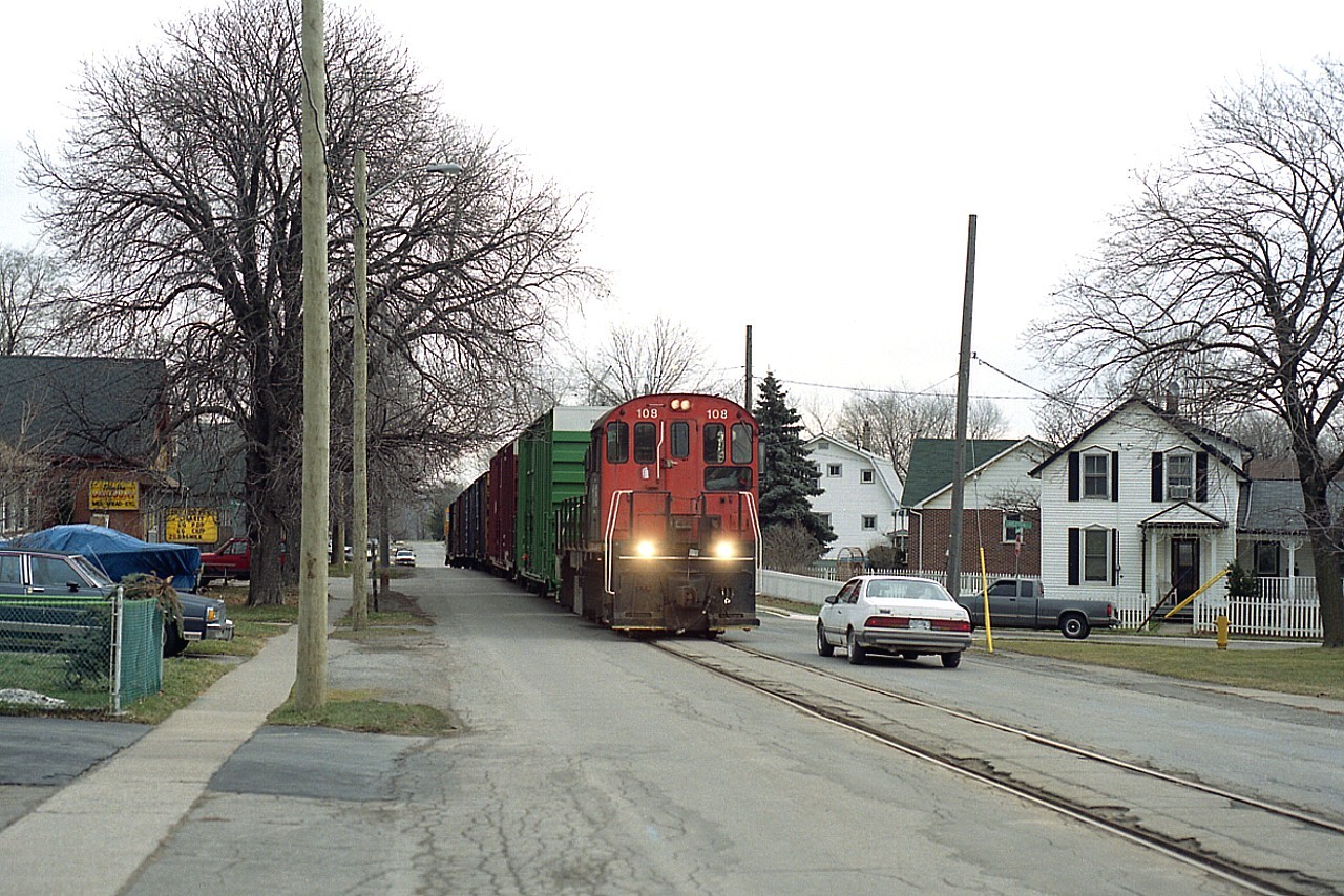 This scene is but a memory as the line is now gone. Trillium 108 is photographed rumbling along the middle of Townline Rd in Welland. For this line, a long train, complete with their rather poor looking caboose on the end. I shot this at distance for a good view of the neighbourhood. Old reliable MLW S-13u began life as CN 8617 way back in 1978, and it is still rolling.  Remarkable, really.