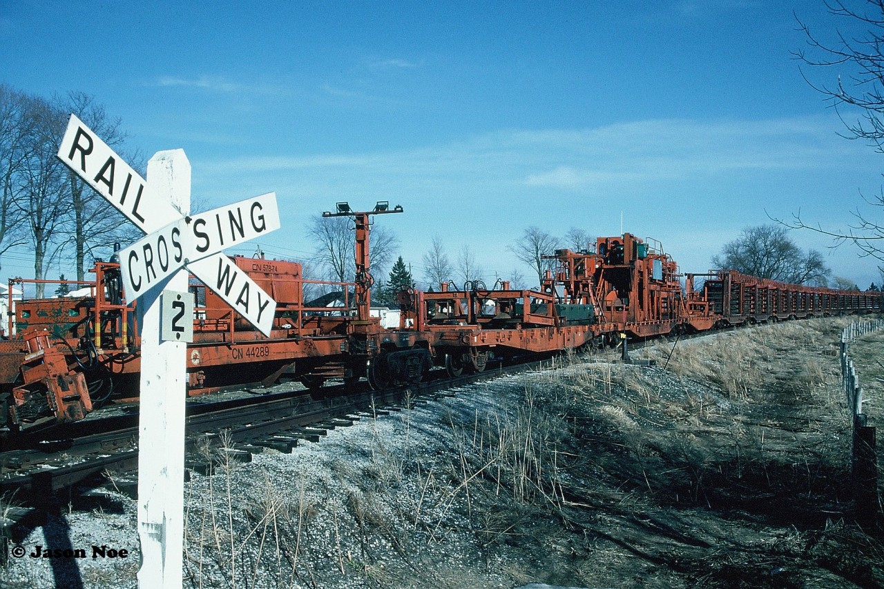 The CN rail salvage train's tail-end is viewed at the Raglan Street crossing in the town of Harriston after arriving from Palmerston. A railway crossing with the old style aluminum cross-bucks still stands guard at the crossing where two tracks crossed. The rail cars would be secured here for the night and the rail removal process would begin in the town the following day.