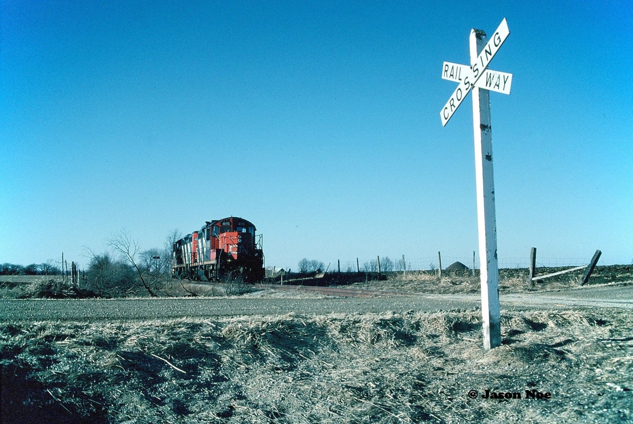 Still standing guard at least for one more day at 7th Line just outside Harriston, the railway crossing sign is seen taking in the last rays of a late winter afternoon. After un-coupling from their empty rail salvage train in Harriston, GP9RM’s 4115 and 4140 made the trek to the quiet dirt road light power and were quickly tied down here by the Stratford crew. A CN vehicle had then arrived and picked them up with the festival city as their ultimate destination from where they had originated earlier in the day. Here, the units sat waiting for the next day, which would see the rail removal process officially begin between Harriston and Listowel.

As some final images were taken, there was actually now time to soak in the moment. No more foremen, no more chasing through towns or on bridges and by oddly placed benches - just the calm rhythmic sound of GP9RM’s. Now idling on rails that once regularly felt the passage of freight and people destined for stations on waybills and stamped on tickets along the route. Photographing what was and knowing what it was about to become are two different things; however in the end they both reach the same conclusion. Unfortunately they become a part of the ultimate history of a rail line.