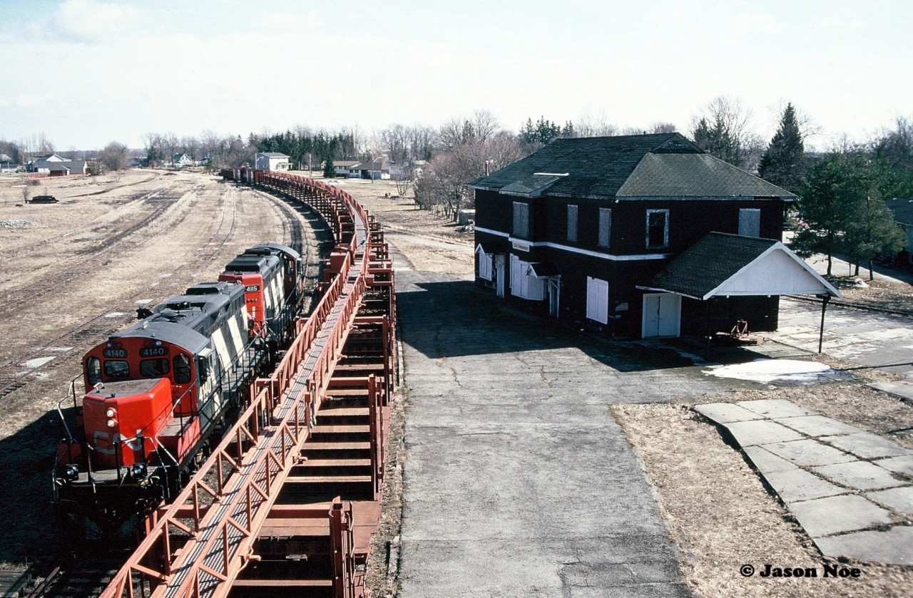 CN GP9RM’s 4115 and 4140 are seen running around their rail train from the town's historic Pedestrian Bridge that spanned the entire Palmerston yard. The dormant CN station is situated on William Street to the right of the cars. 

From here, once the run-around was complete the units would couple to the south end of the cars to await the final portion of their trip to Harriston. From Palmerston, they would shove the remaining five miles to Harriston on the Owen Sound Subdivision.