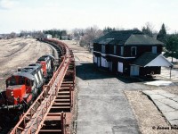 CN GP9RM’s 4115 and 4140 are seen running around their rail train from the town's historic Pedestrian Bridge that spanned the entire Palmerston yard. The dormant CN station is situated on William Street to the right of the cars. 
<br>
From here, once the run-around was complete the units would couple to the south end of the cars to await the final portion of their trip to Harriston. From Palmerston, they would shove the remaining five miles to Harriston on the Owen Sound Subdivision.
