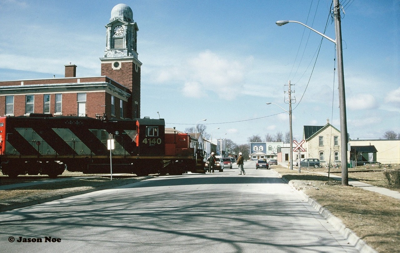 During the afternoon of April 1, 1996 CN 4140 and 4115 had arrived in Palmerston and are seen crossing William Street with the rail train from Stratford as several locals had eventually emerged to take in the action.