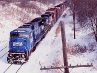 All the extra notches on the old telephone poles tell the tel of just how important they once were. NS train 327 is seen digging into the grade as it follows the unused pole line along CN's Dundas subdivision at Copetown. The train has about a mile to go before it will stop climbing the Niagara Escarpment, with a final destination of Talbotville. Relatively clean former Conrail SD60I 6727 is on the point as it and a standard cab Dash-9 roll along the frozen landscape.