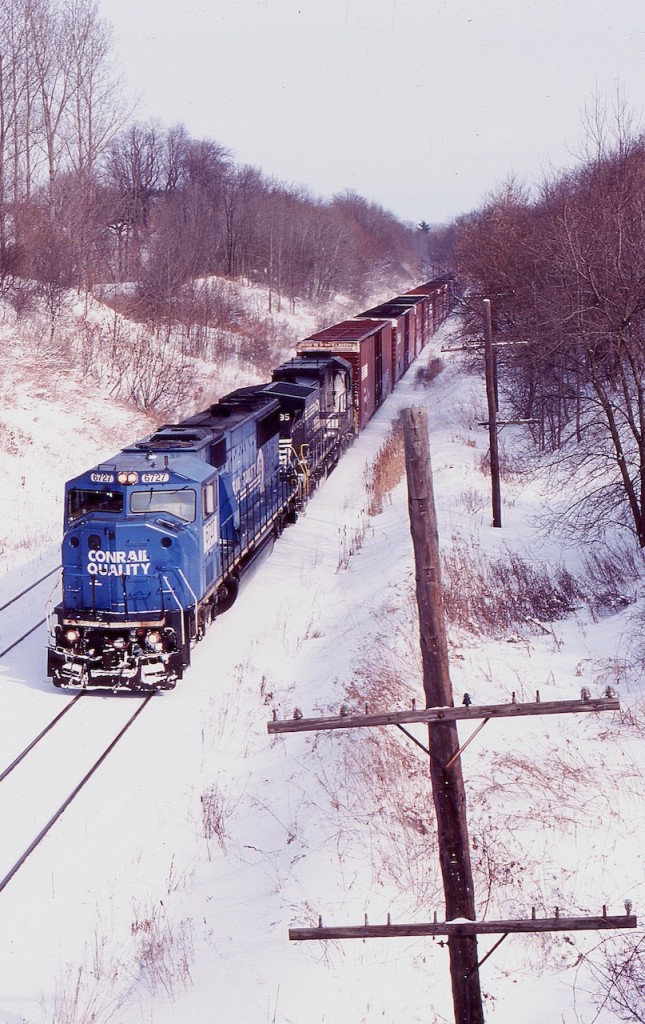 All the extra notches on the old telephone poles tell the tel of just how important they once were. NS train 327 is seen digging into the grade as it follows the unused pole line along CN's Dundas subdivision at Copetown. The train has about a mile to go before it will stop climbing the Niagara Escarpment, with a final destination of Talbotville. Relatively clean former Conrail SD60I 6727 is on the point as it and a standard cab Dash-9 roll along the frozen landscape.
