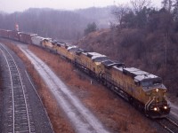 Definitely not one of the best lit slides I have ever taken but considering the situation this day shooting in the pouring rain was a must. At the time for the past few weeks the NS 327/328 trains were somewhat sporadic, some days running, some days not and others just light power. Knowing there were two sets of power the day before in St. Thomas, and hearing NS may only run a train or two before the end of service in only a few days, I took the gamble and headed out to Hamilton Junction. As the rain poured down I did the best I could to cover both camera and video camera. NS 328 was very slow moving this day considering it had four borrowed UP units. It turned out to be the longest train 328 I ever shot at near to 120 cars. As it turned out I believe NS 327/328 may have run only a couple more times with only a few cars or just light power. It was sad to witness the event with so much history behind these NS trains all coming to an end. CN would handle the traffic after this but only for a couple more years as the writing was on the wall for the old Ford assembly plant in Talbotville as production soon came to an end and the plant was closed and eventually demolished. Things just are not the same around St. Thomas, the one time railroad capital of Canada.