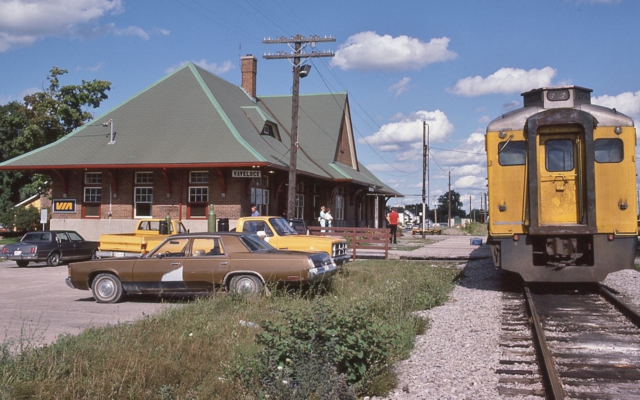 Awaiting the arrival of the crew for the 17:45 departure, the usual ubiquitous pair of ex CP Rail Budds is the equipment for Sunday only VIA Rail train #189


   at Havelock *,  August 4, 1986 Kodachrome by S.Danko. 

 

   Interesting: Havelock Budd's canceled September 6, 1982; restored June 3, 1985, canceled January 14, 1990.


   *  Station construction by CPR commenced 1914, interrupted by WWI, completed 1929. 


   Completed in August 1884 the Ontario & Quebec Railway (Perth to North Toronto) subsequently signed a lease agreement that expires in 2883.


   The 999 year leases allows the CPR absolute and complete control of the O & Q assets confirmed per a 1980 era court ruling as a result of legal action by some minority O & Q shareholders.


   The lease agreement, along with other lease agreements with the Toronto Grey & Bruce, Credit Valley Railway and  the West Ontario Pacific Railway (WORP) (leased to the O & Q in 1883), which connected the Credit Valley in Woodstock to Windsor and the US border, formed major components of the CPR network in southern Ontario.


   The January 14, 1990 cessation of Havelock Sub passenger service, CP Rail issued a new employee time table,  the following station names [were] removed from the Havelock Subdivision: Indian River; Manvers, Burketon, Dagma, Locust Hill, and Tapscott. (per UCRS Newsletter February 1990). And the Havelock Sub speed limit reduced to a maximum 30 m.p.h.


   And the vehicles: all American iron: at left the ever popular Oldsmobile Cutlass sedan ( likely a GM Canada Oshawa build) , Chevy pickup, GMC Pick up, and a brown Chrysler Newport sedan. 



      at Peterboro 


    sdfourty