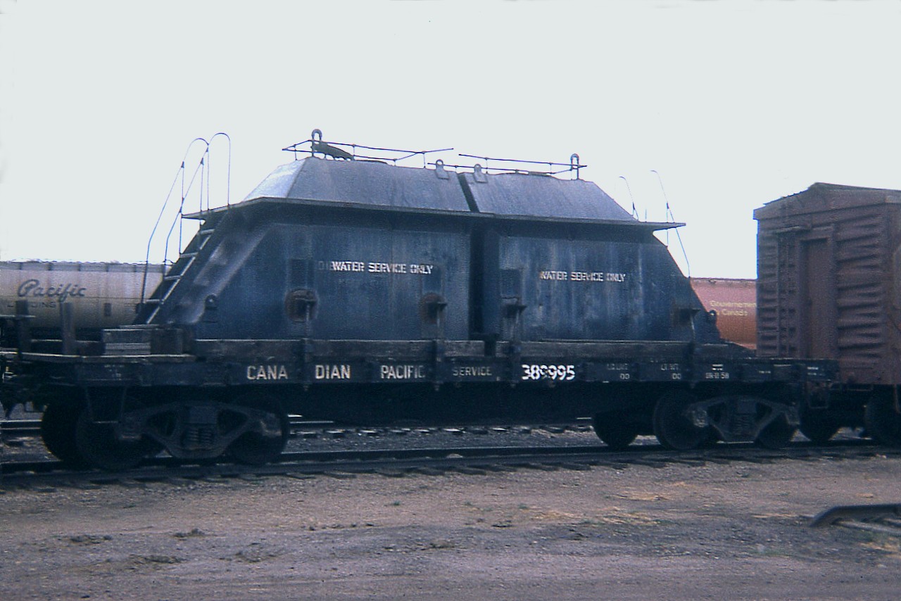 I am just putting this image out to the group in order that perhaps I could get some information on this car. I have not seen another one like it, and this image is 47 years old. Not sure of the location either, but I was out west at the time and I believe this was at Medicine Hat, as I shot other photos there. Can anyone identify this as to number of them, what was it originally, why styled in this manner and what became of them? I have nothing to go by, and my 1968 Equipment guide has tank cars numbered up to 389989; but no mention of a 389995.
The 1975 Guide shows this as one of 4 'tank cars' left in a series 389990-389995; but for water ??  THANKS